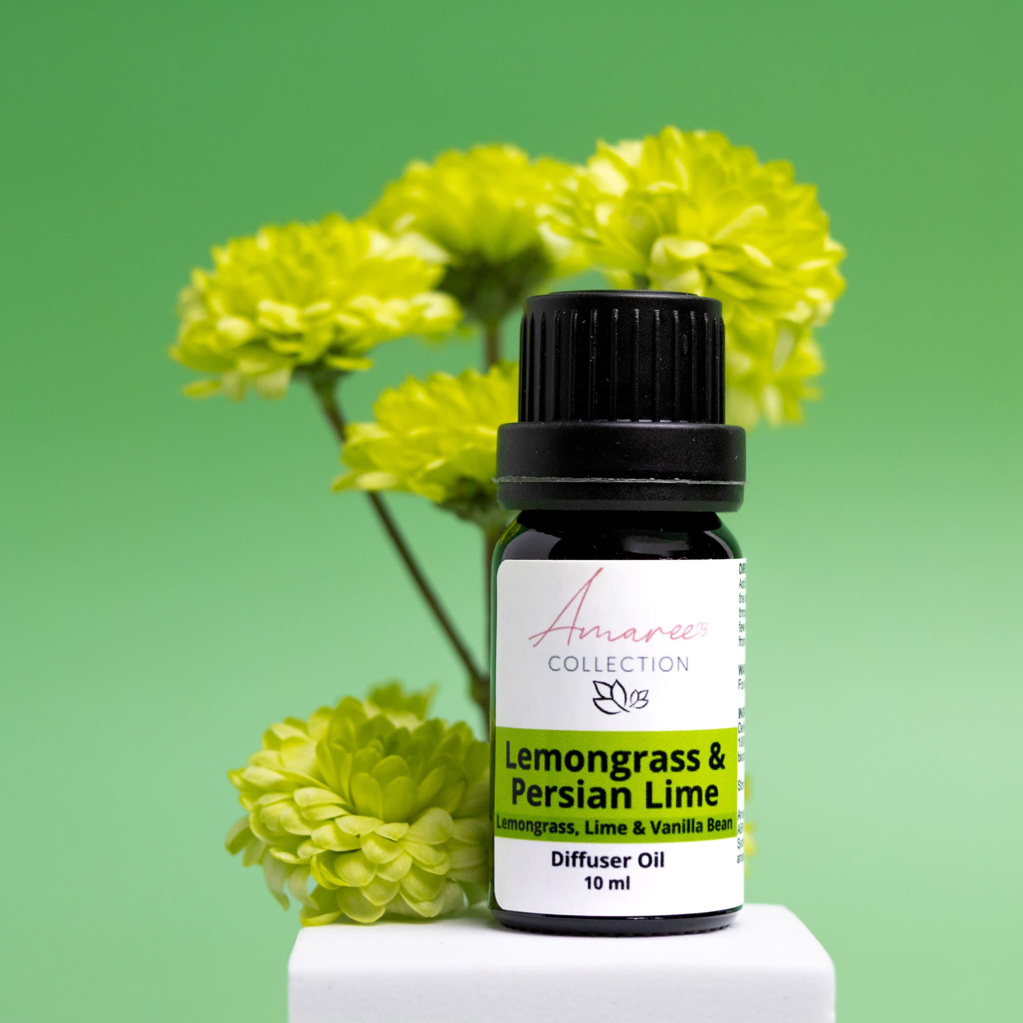 Lemongrass & Persian Lime diffuser oil bottle with green flowers on a green background