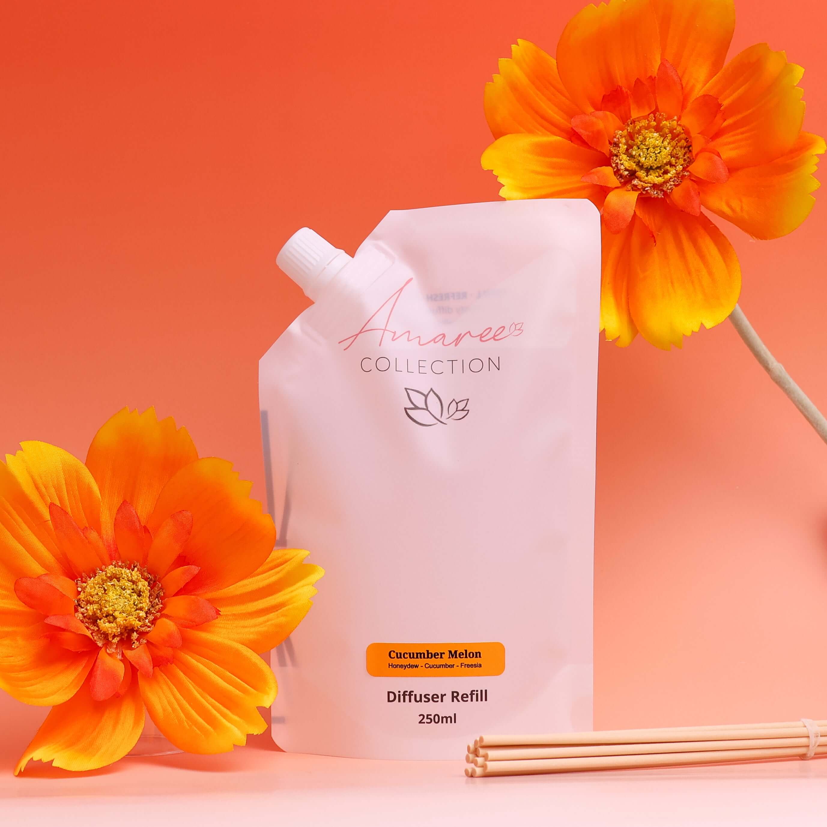 Cucumber Melon Reed Diffuser Refill 250ml packaging with bright orange flowers on a pink background.