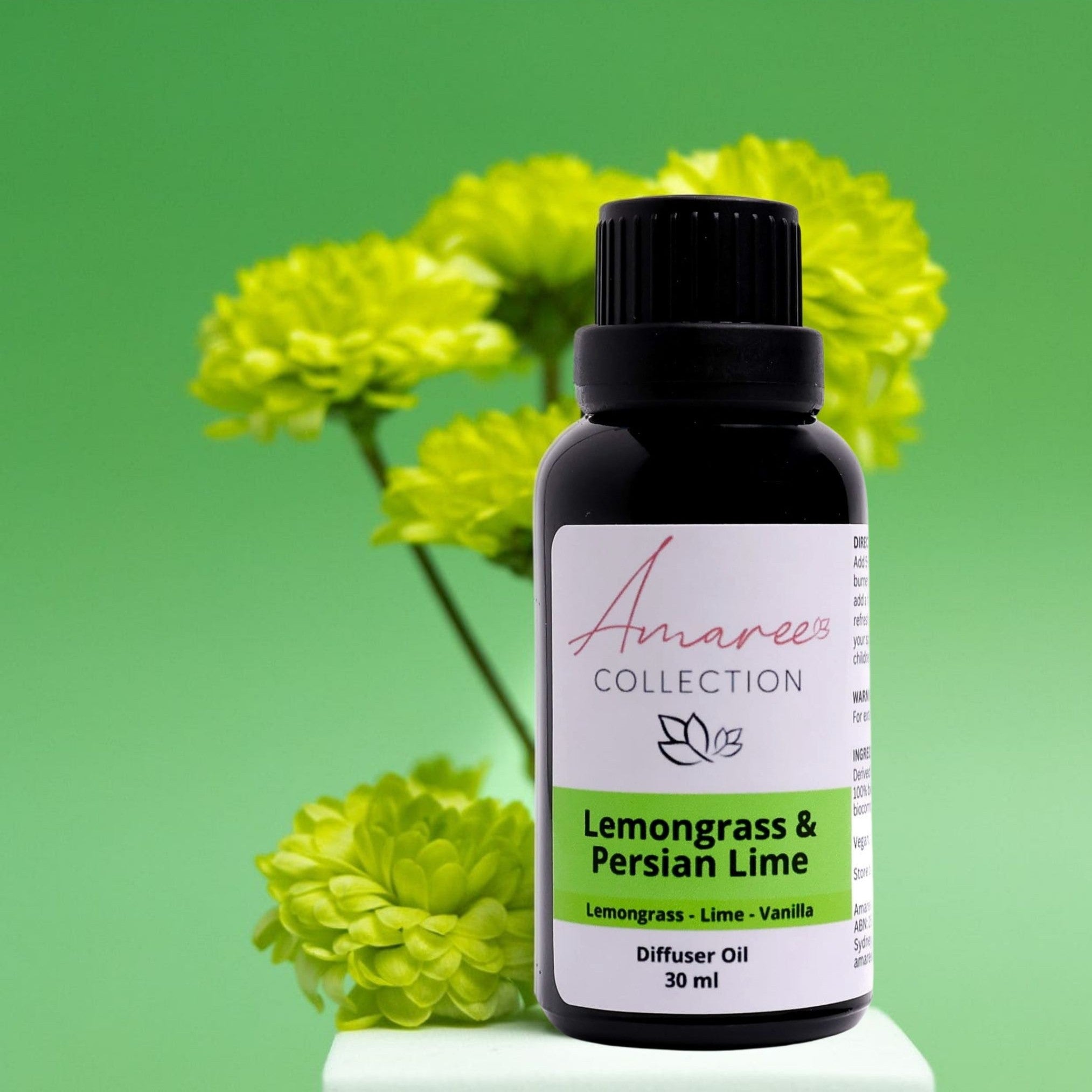 Amaree Collection diffuser oil bottle with lemongrass and Persian lime scent against a green background with flowers.
