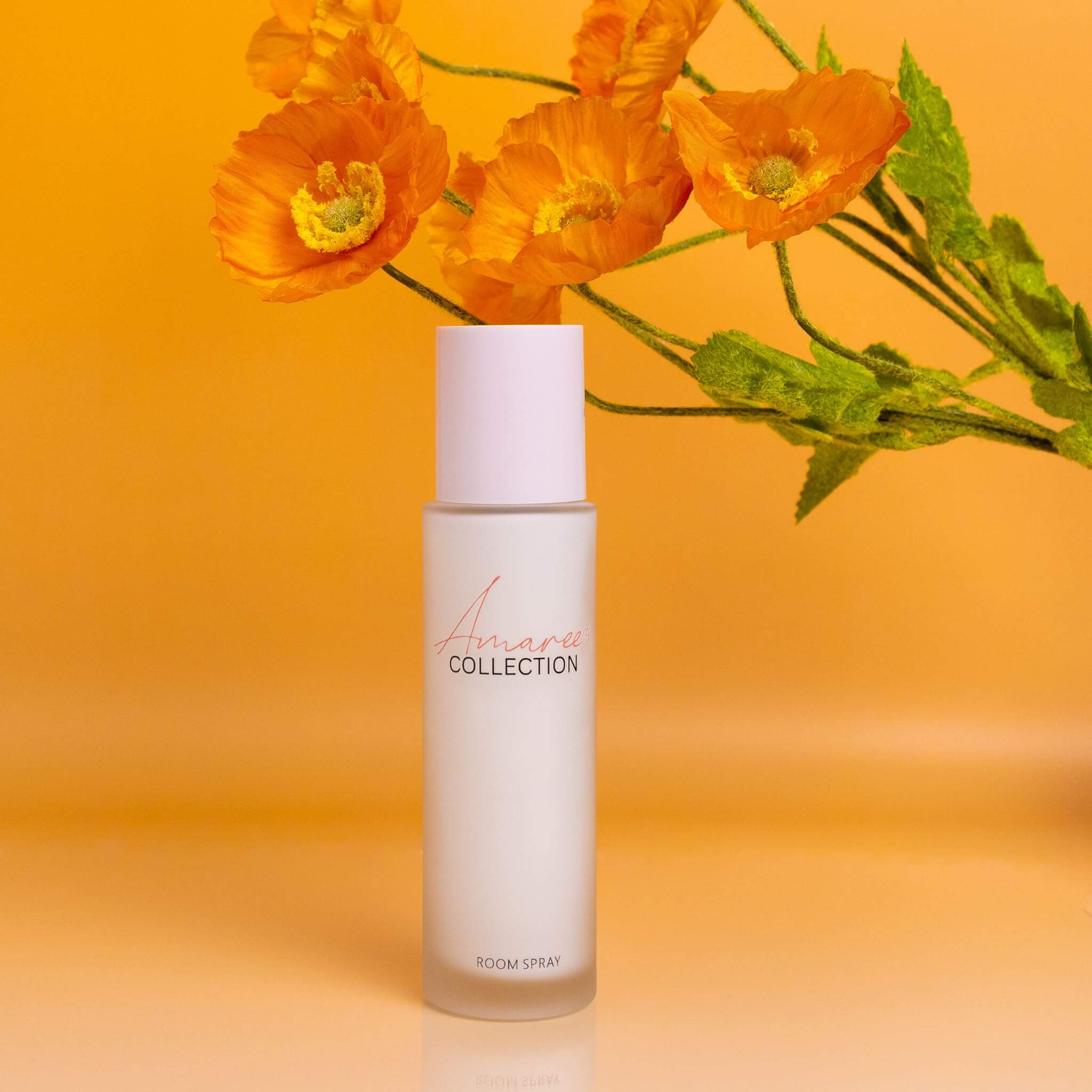 Lime, Basil & Mandarin Room Spray 100ml displayed with vibrant orange flowers on a bright background.