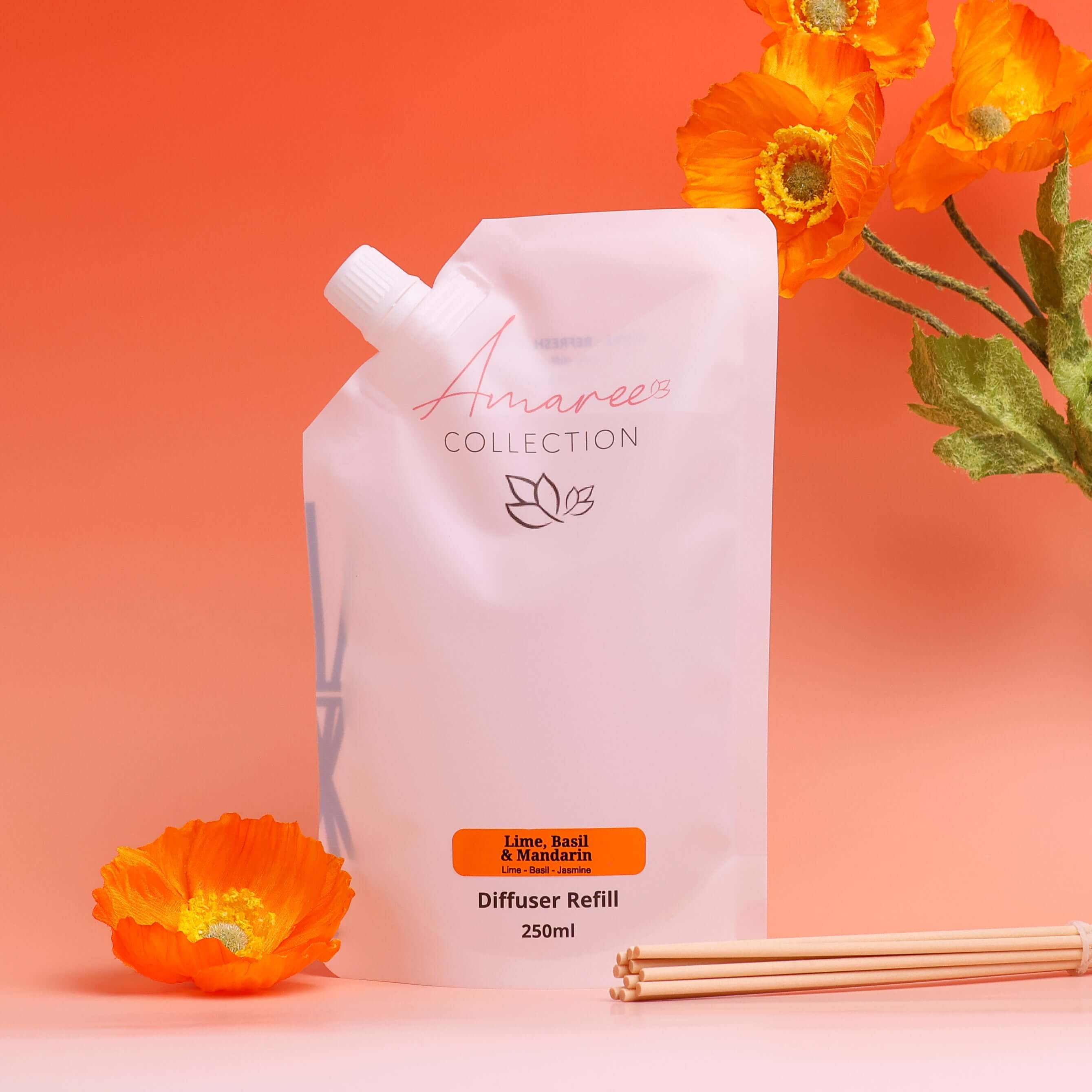 lime basil mandarin reed diffuser refill 250ml pouch with orange flowers and reeds on coral background