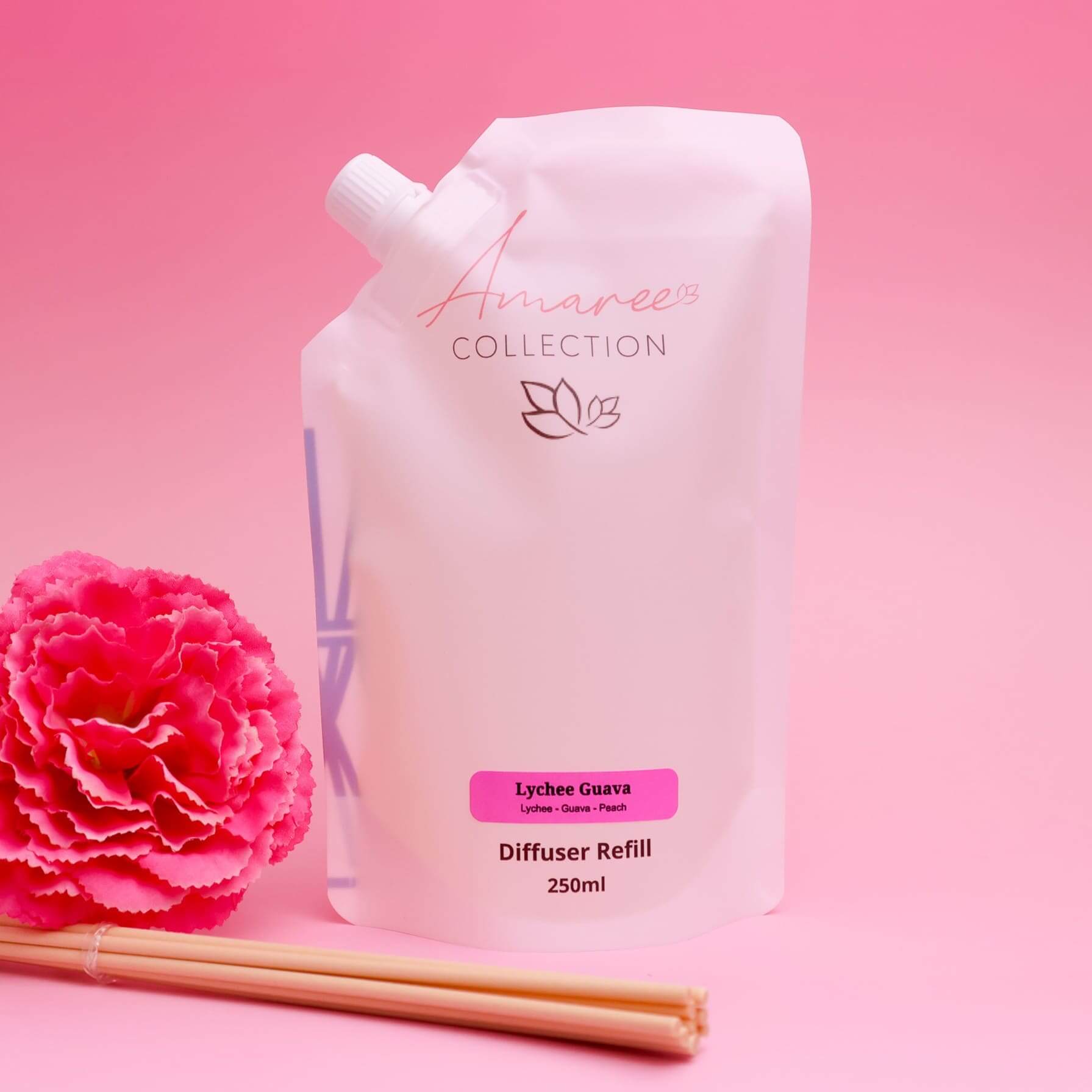 Lychee Guava Reed Diffuser Refill 250ml in a pink pouch with a flower and diffuser sticks.