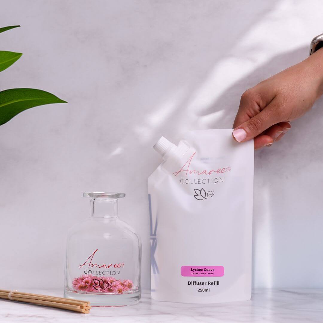 Lychee Guava Reed Diffuser Refill 250ml with decorative glass diffuser and plant on a marble surface.