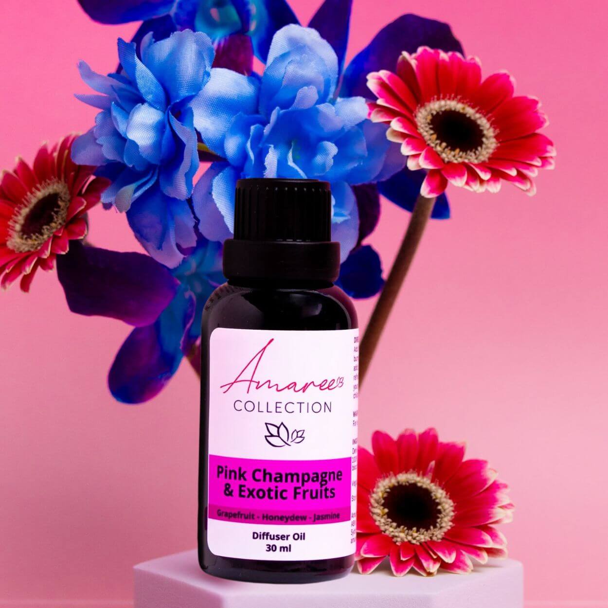 Pink Champagne & Exotic Fruits Diffuser Oil in a floral setting, showcasing a vibrant and fruity scent experience.