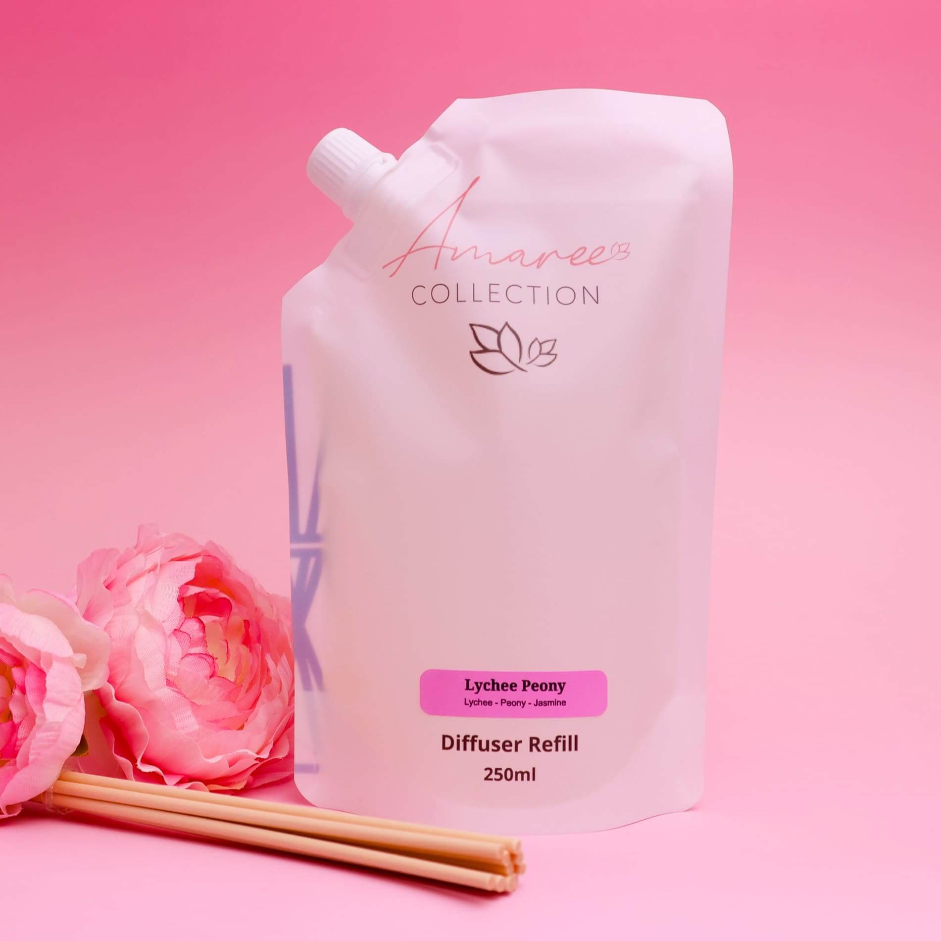 Lychee Peony Reed Diffuser Refill 250ml in elegant pouch with flowers on pink background.