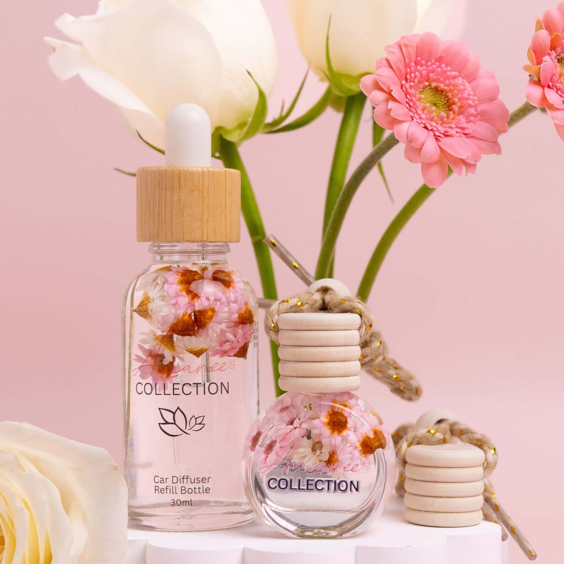 Sheer Lily & White Rose Car Diffuser Kit shown with floral design bottles on a pink background.
