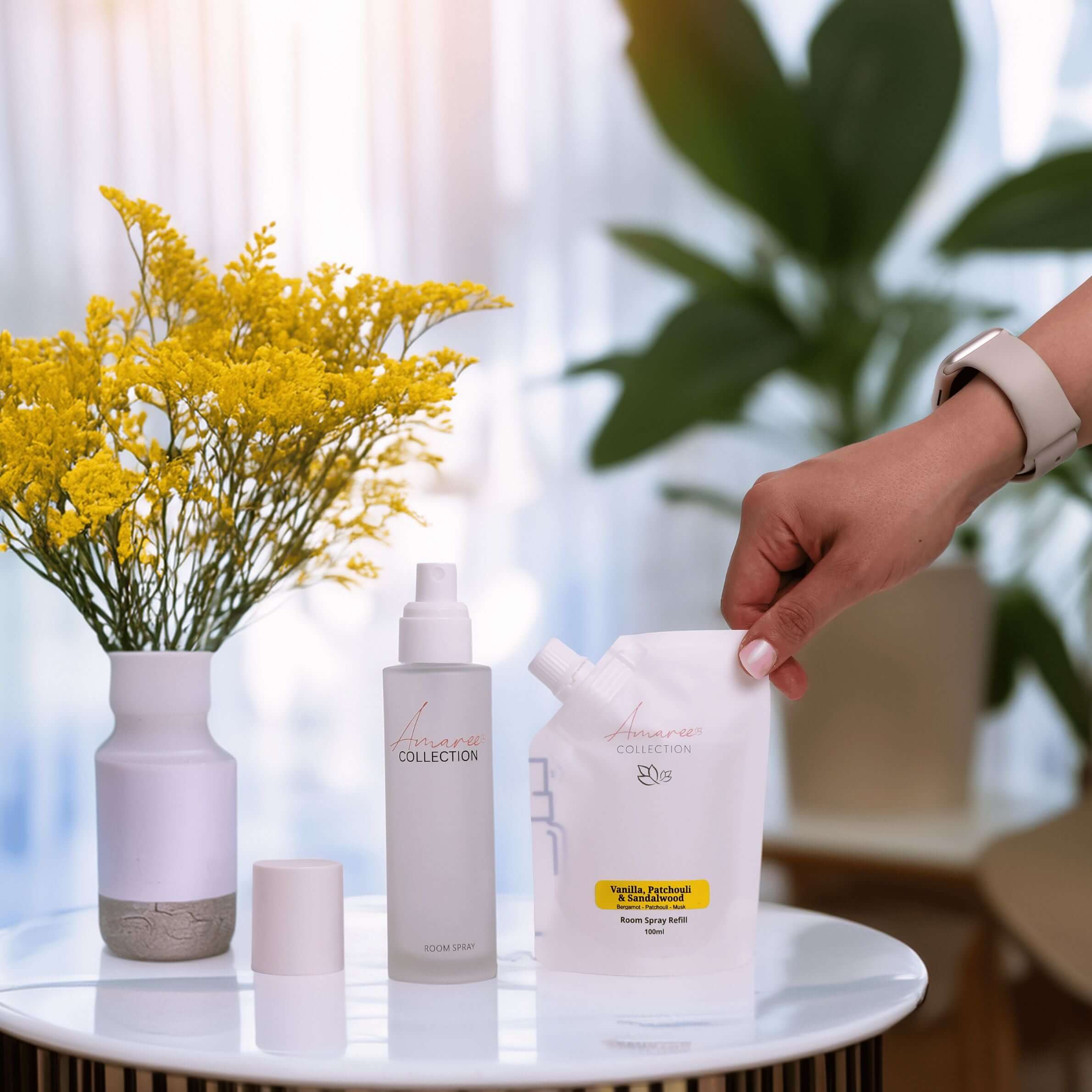 Vanilla Patchouli & Sandalwood Room Spray Refill 100ml displayed with stylish vase and flowers on a modern table.