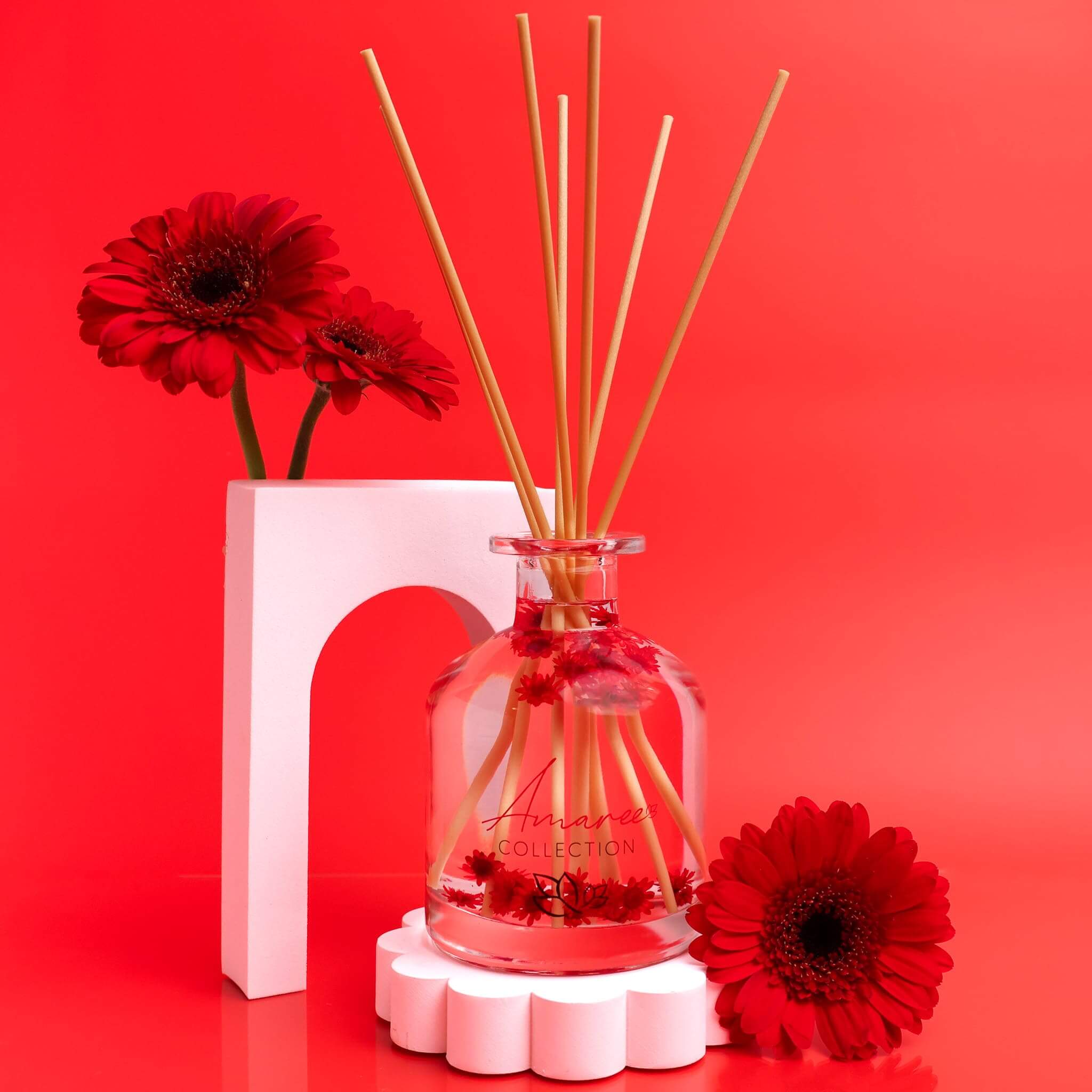 Black Raspberry & Vanilla Reed Diffuser 250ml with floral decor on a vibrant red background.