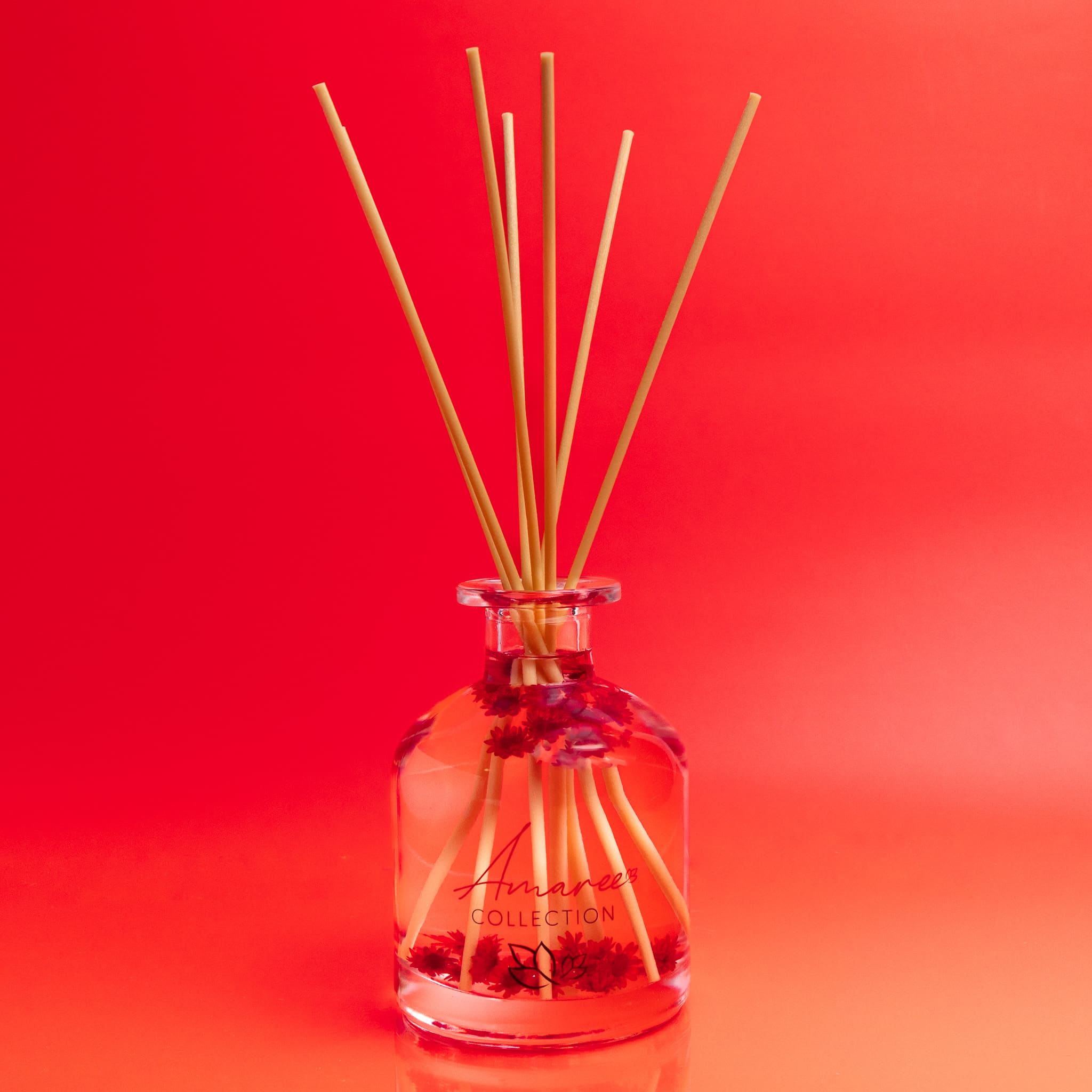 Reed diffuser with wooden sticks in a clear bottle on a red background