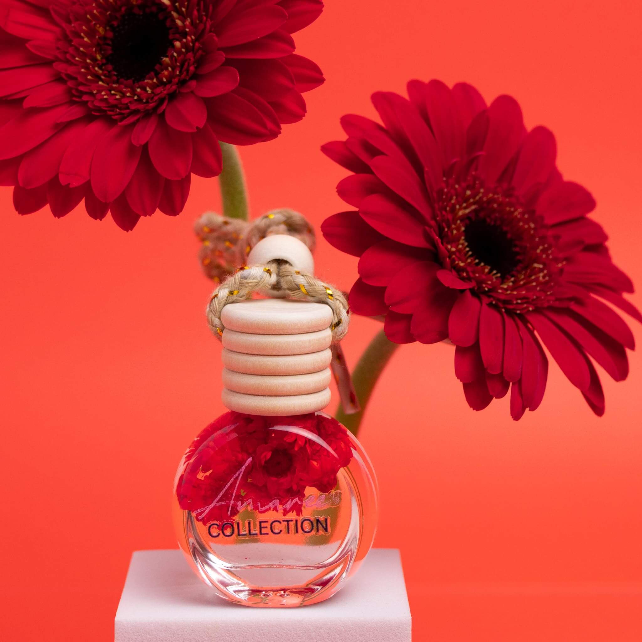 Black Raspberry & Vanilla Car Diffuser with vibrant red flowers in a bright background.