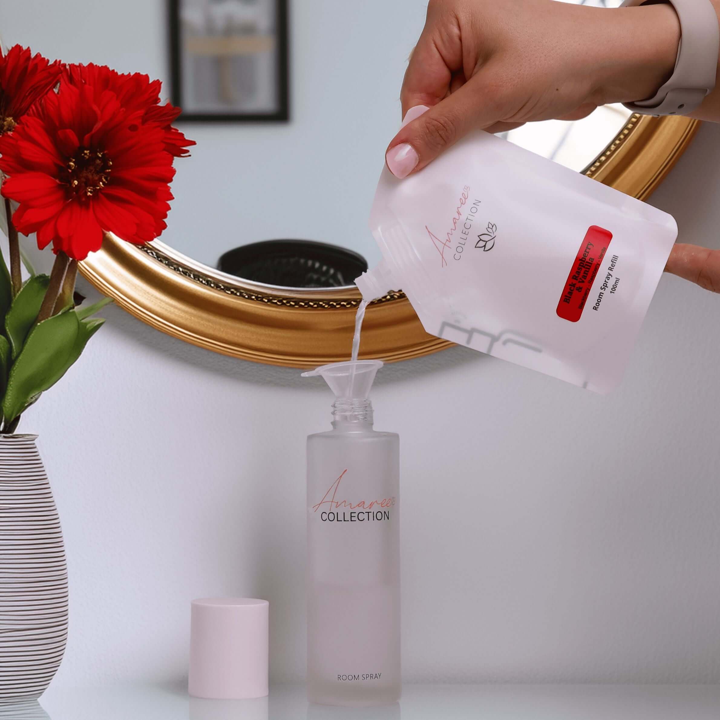 User refilling Black Raspberry & Vanilla Room Spray Refill 100ml into a clear spray bottle.