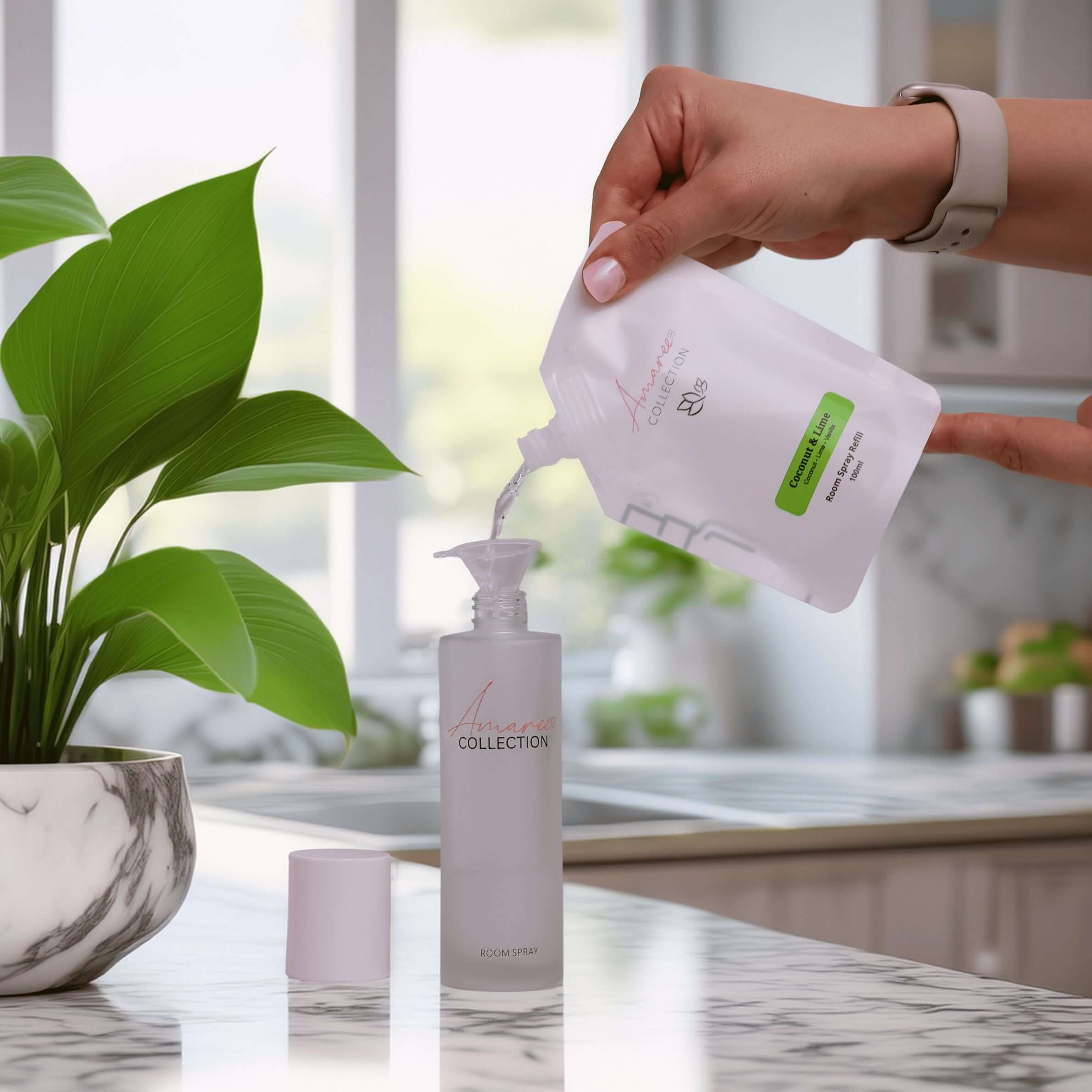 Coconut Lime Room Spray Refill 100ml being poured into a stylish bottle in a bright kitchen setting.