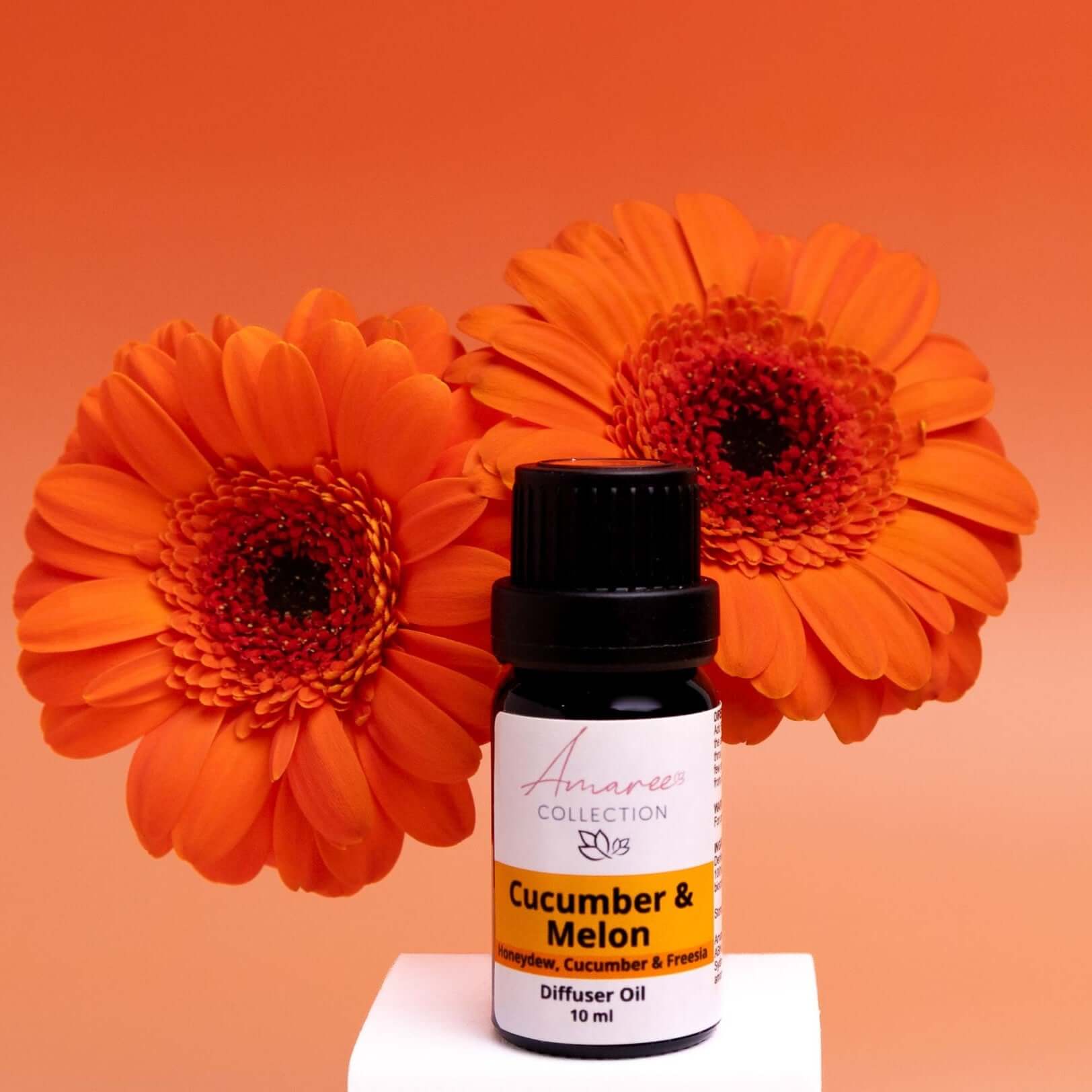 Cucumber Melon Diffuser Oil bottle with orange flowers in the background, showcasing a refreshing scent for home fragrance.