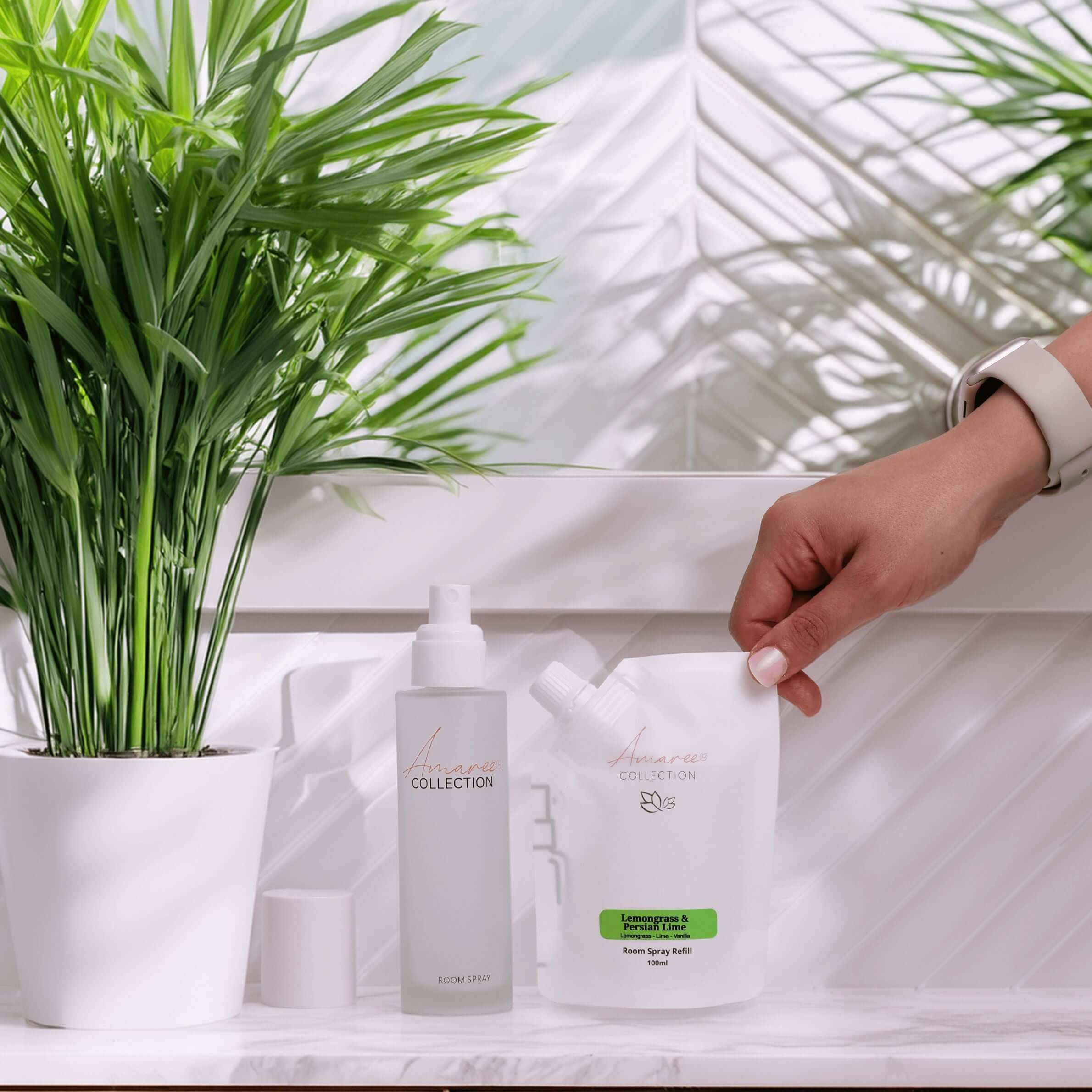 Lemongrass Room Spray Refill 100ml being used next to potted plant in modern bathroom setting.