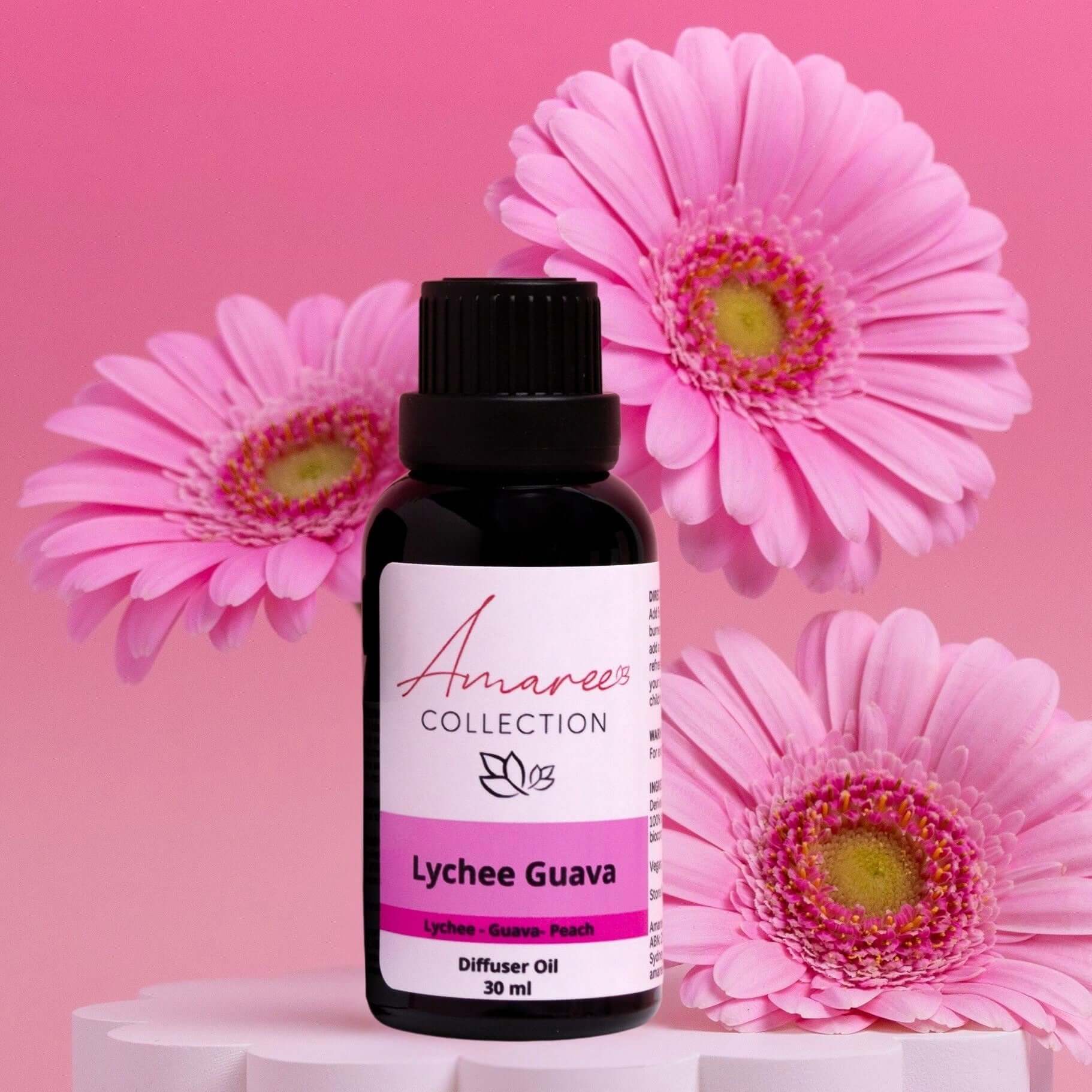 Lychee Guava Diffuser Oil in a bottle surrounded by pink flowers, offering a fruity and fresh scent experience.