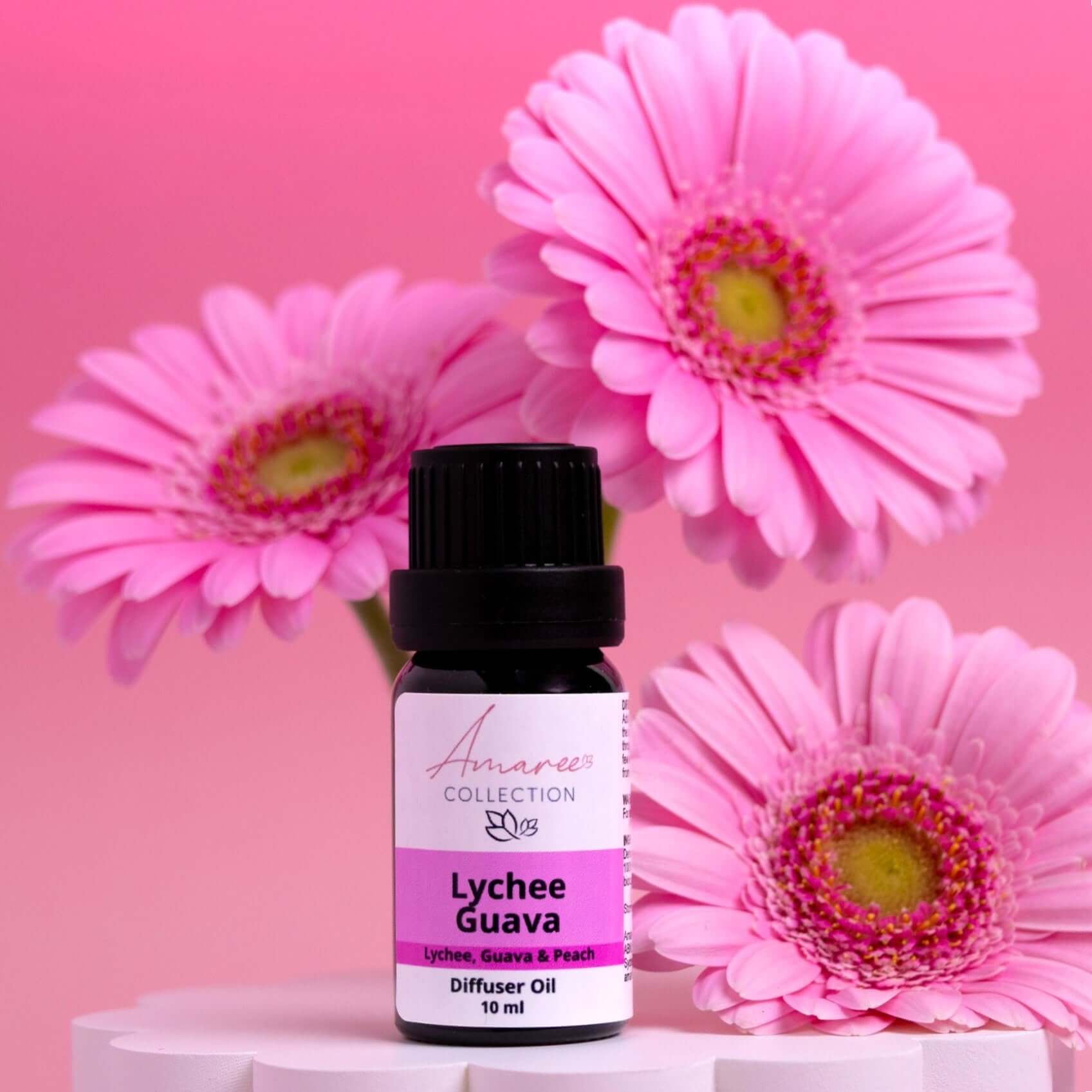 Lychee Guava Diffuser Oil bottle surrounded by pink daisies, showcasing fruity scent and tropical vibes.