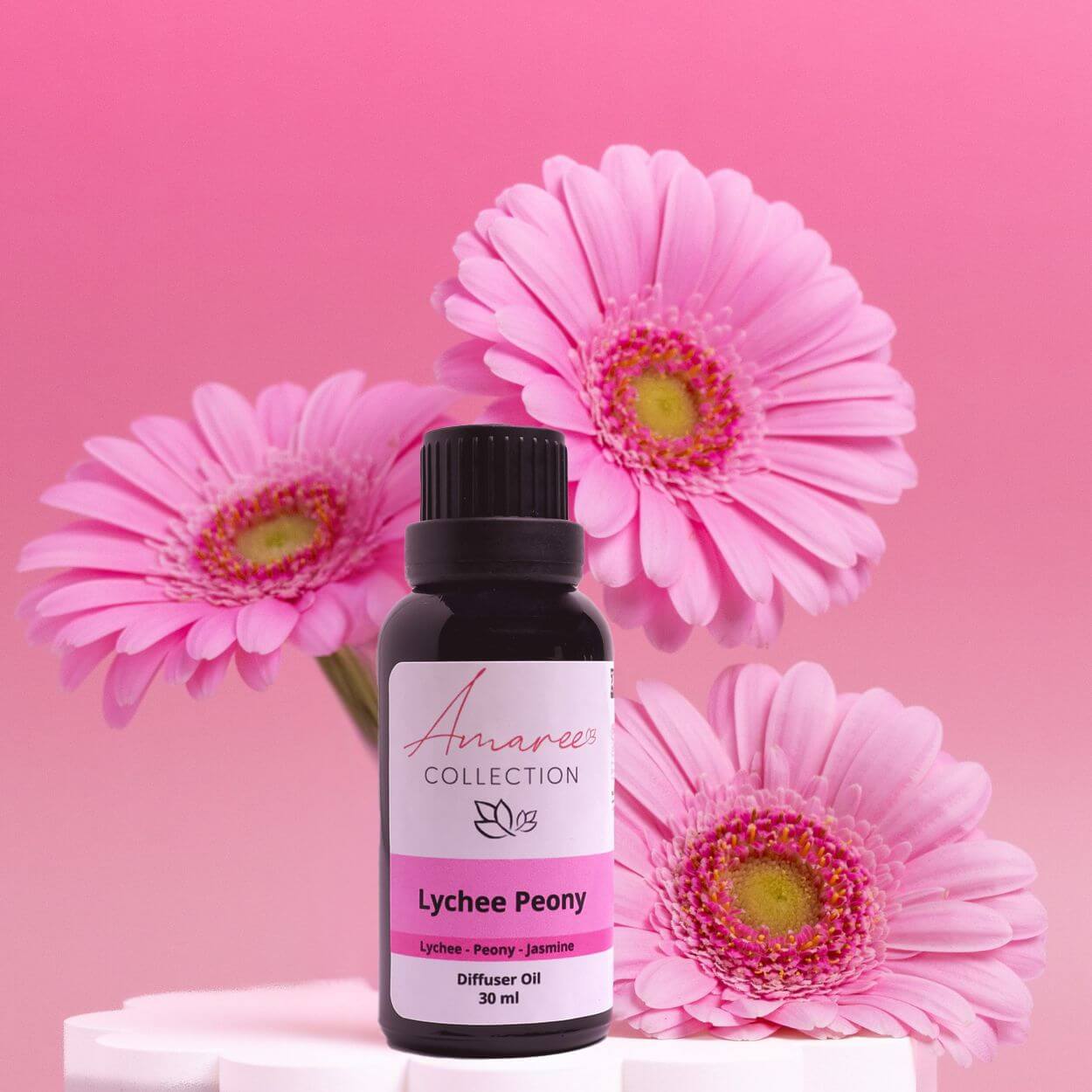Lychee Peony Diffuser Oil with pink flowers in the background, showcasing its delicate floral scent.