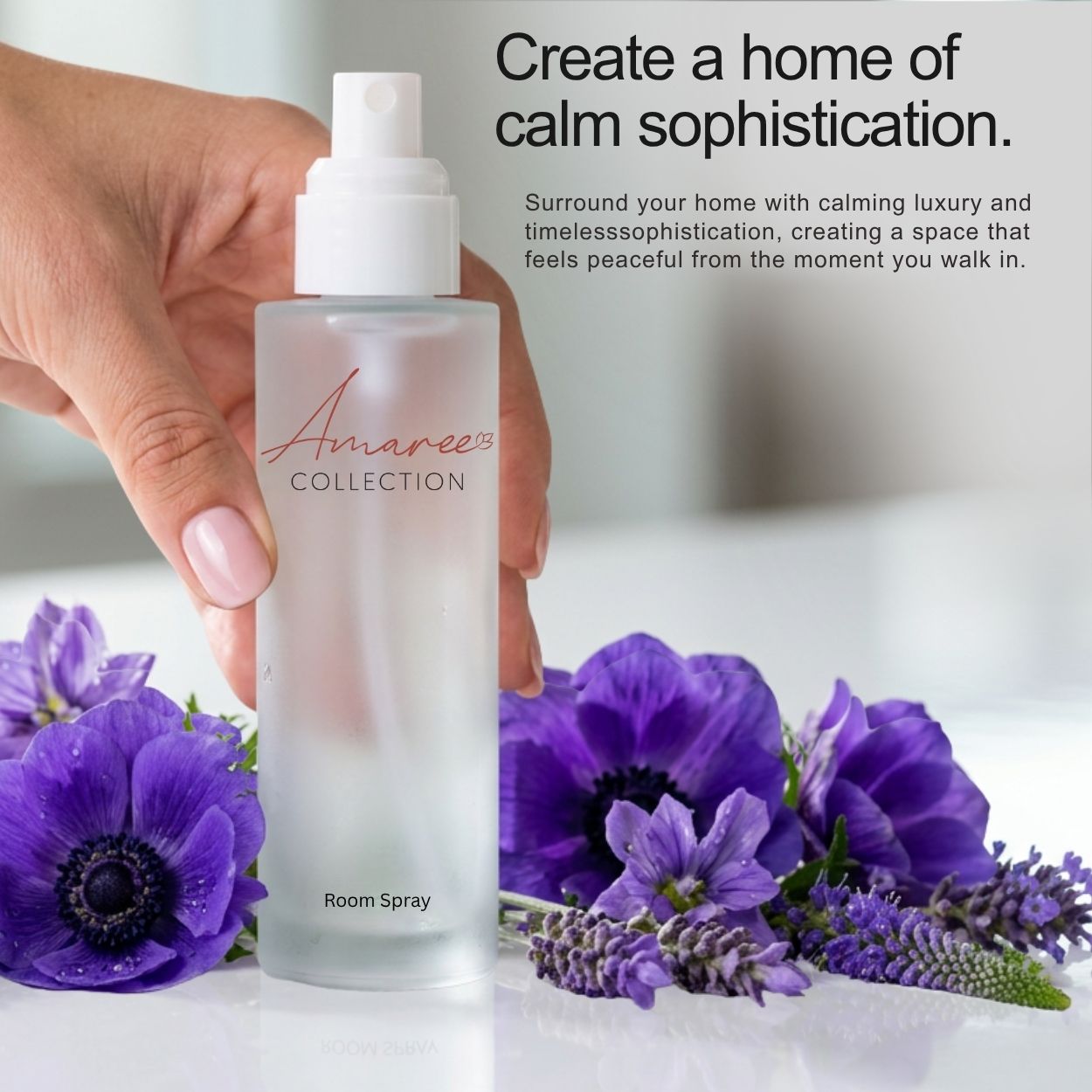 A hand holds a frosted glass room spray bottle labeled &