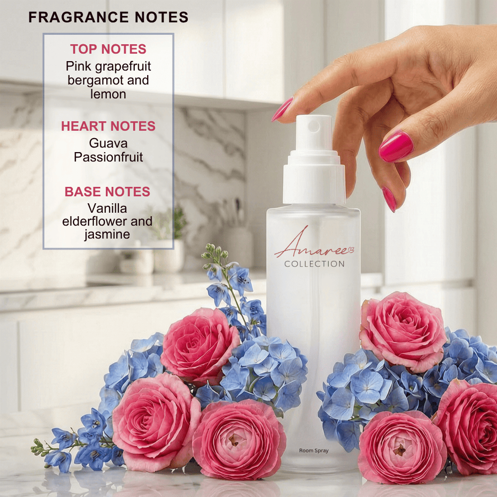 A frosted glass room spray bottle from the Amaree Collection, being sprayed by a hand with bright pink nails. The bottle is surrounded by pink roses and blue flowers on a marble countertop, with a fragrance notes graphic overlay on the left.