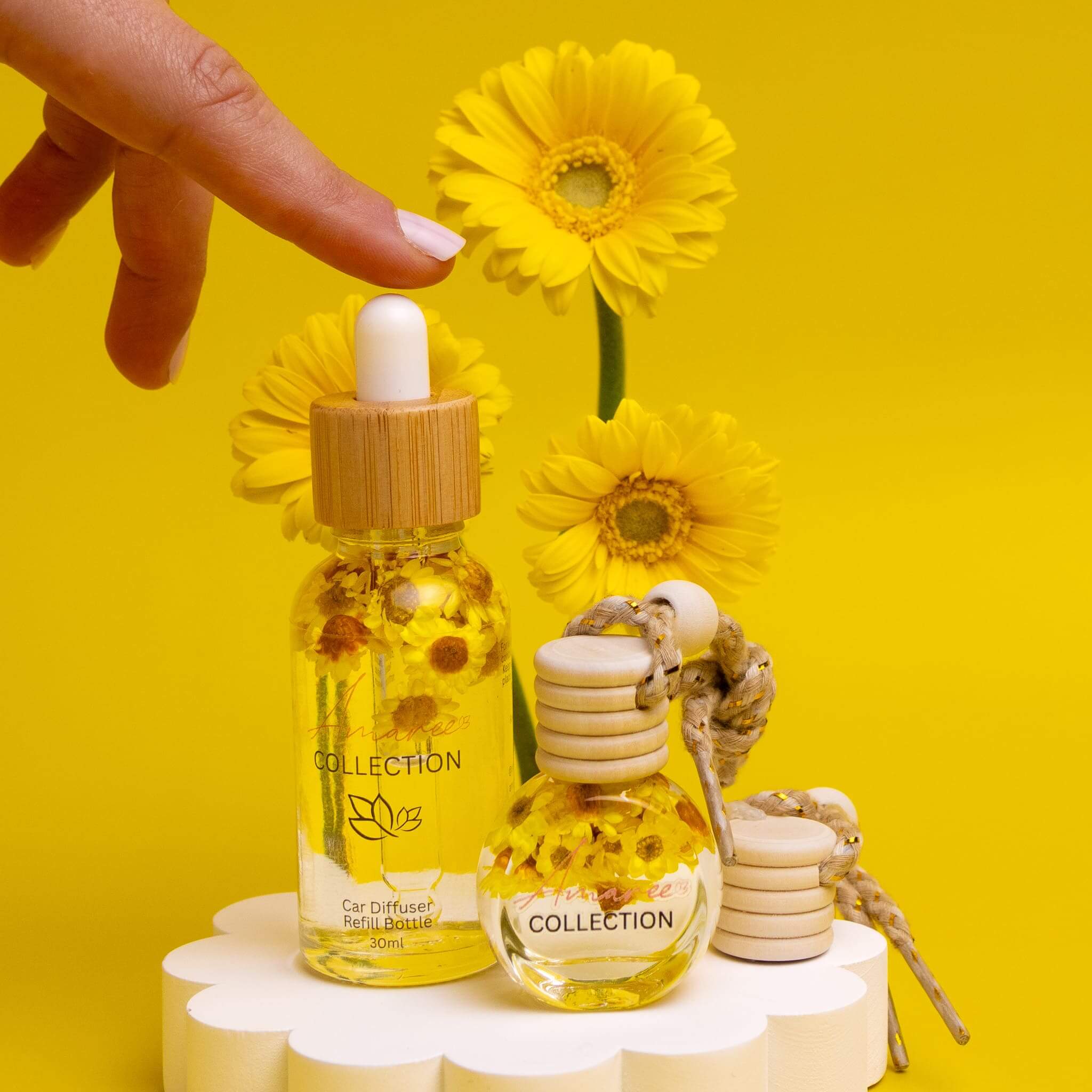 Vanilla Patchouli & Sandalwood Car Diffuser Kit with floral accents on a bright yellow background.