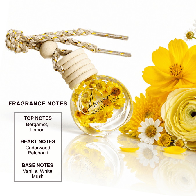 A clear glass reed diffuser bottle with a cream-colored wooden stopper and braided cord, filled with dried yellow flowers. The bottle is shown on a reflective white surface next to yellow flowers, with a text box detailing the fragrance notes: Bergamot, Lemon, Cedarwood, Patchouli, Vanilla, and Musk.