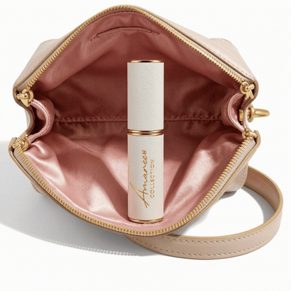 An open blush pink zippered cosmetic pouch with gold-tone hardware, containing a white cylindrical cosmetic tube with gold trim and the visible brand name &