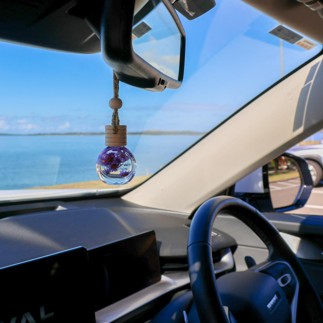 Black Amber &amp; Lavender Car Diffuser hanging in car interior with calming floral woody scent by the ocean