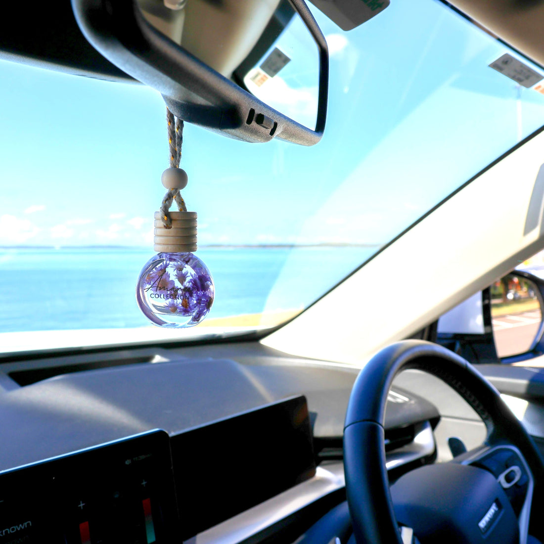 Car interior with a purple hanging ornament on the rearview mirror