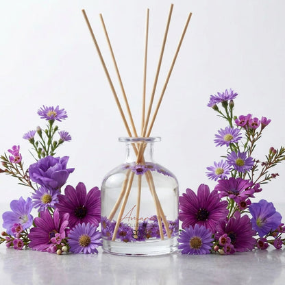 Japanese Honeysuckle Home fragrance diffuser bottle with wooden sticks surrounded by purple flowers on a white background