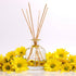 Reed diffuser with wooden sticks and yellow flowers on a light background