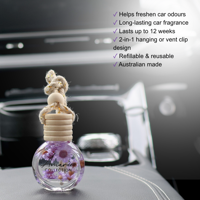 A car air freshener bottle with purple flowers inside, featuring a beige rope knot and wooden cap, shown on a car dashboard with promotional text on a black background.