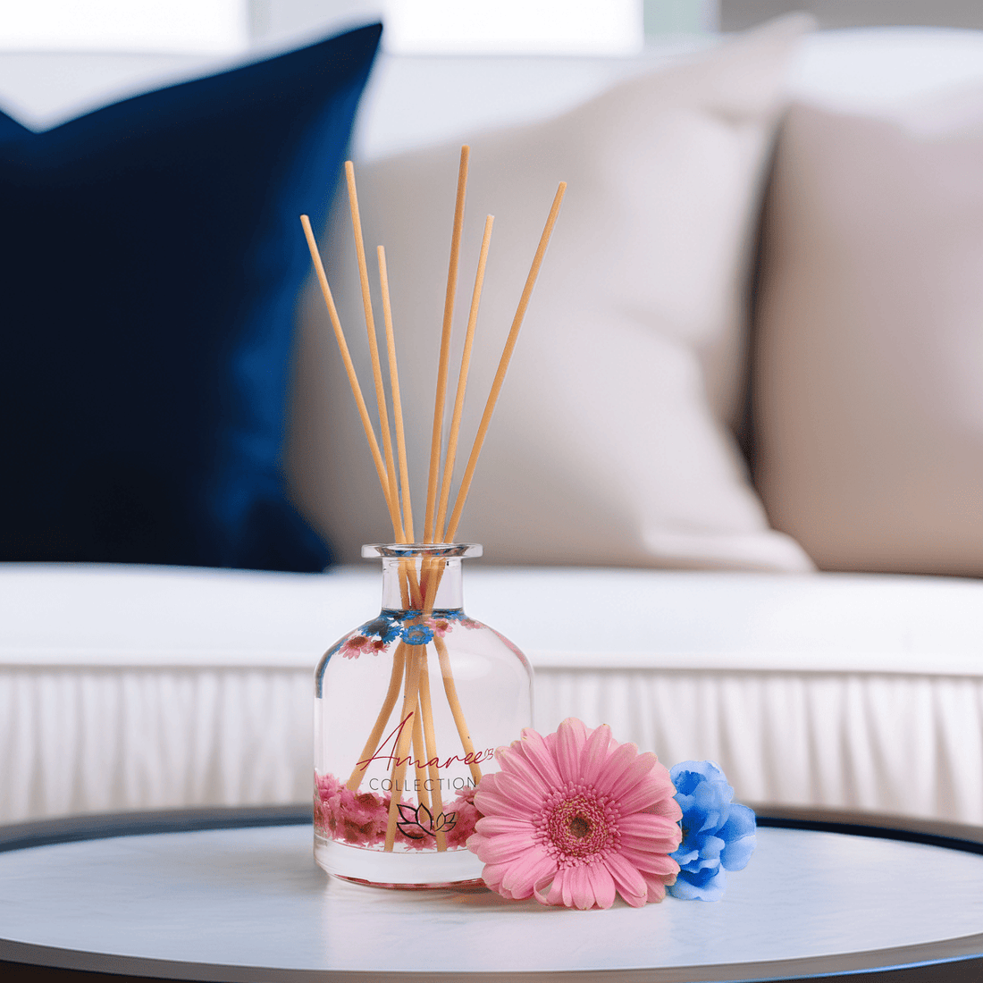 reed diffuser with pink and blue flowers styled on a coffee table 
