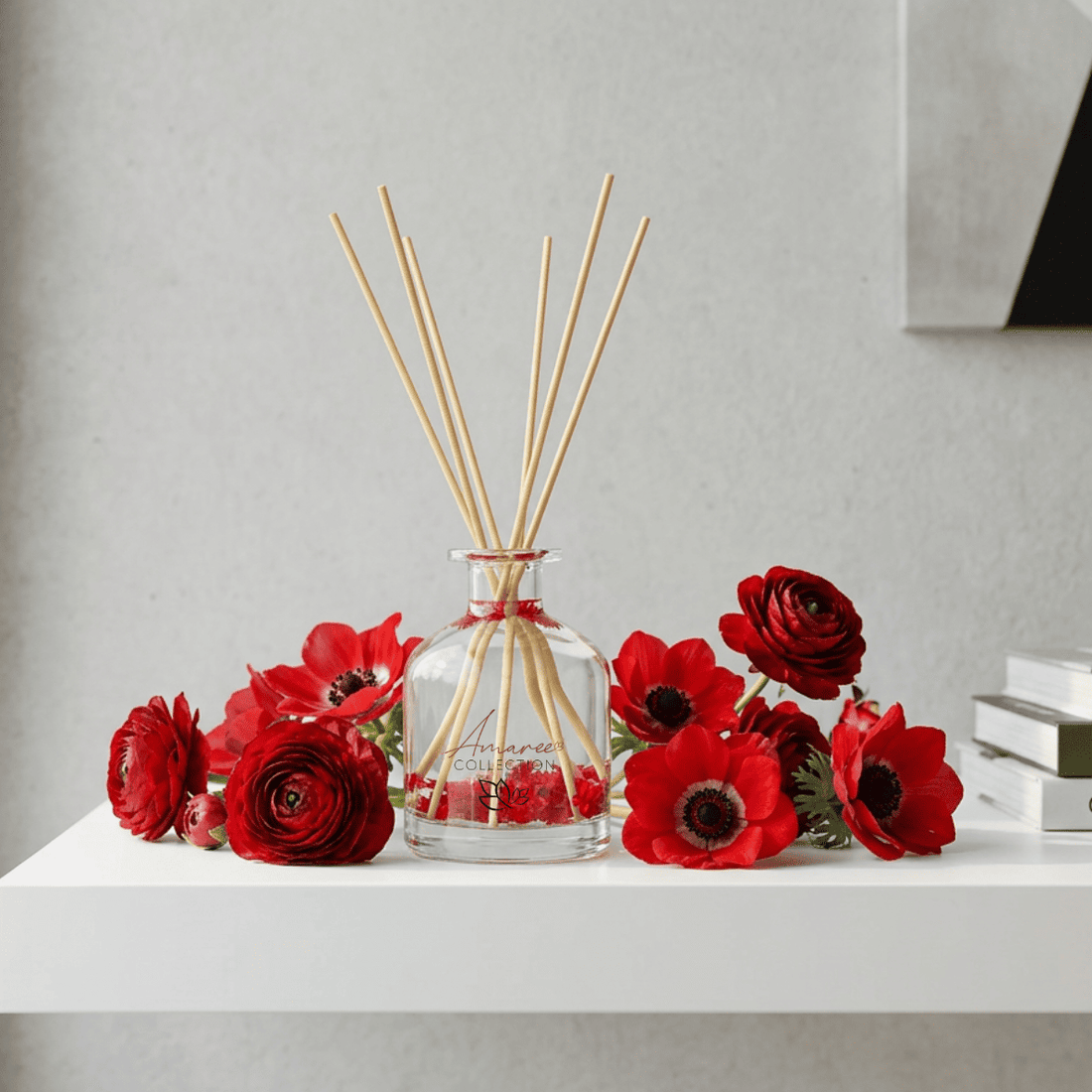 Glass diffuser with wooden sticks and red flowers on a white surface