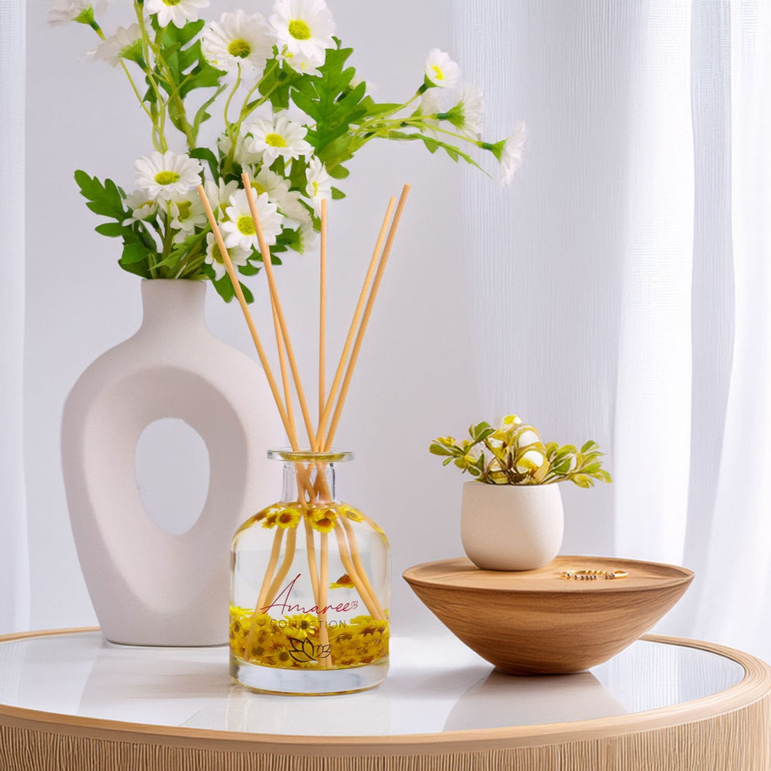 Decorative items including a vase with flowers, diffuser, and small plant on a table.