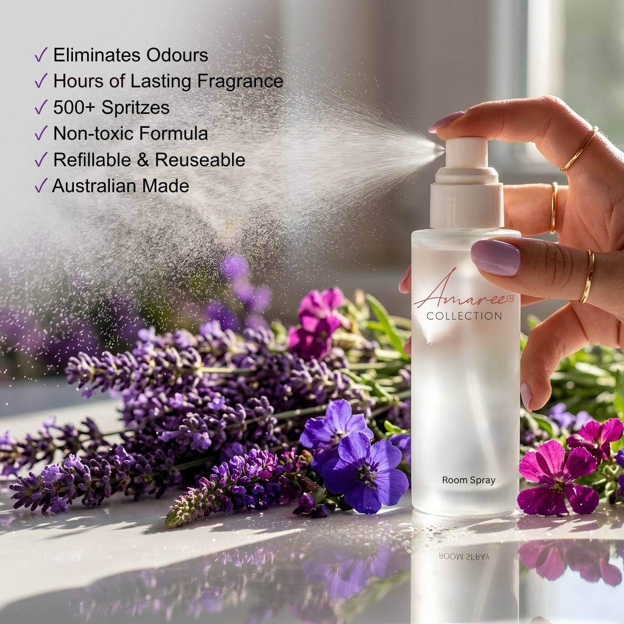 A hand sprays a bottle of room spray, with visible mist coming out. The bottle is labeled &