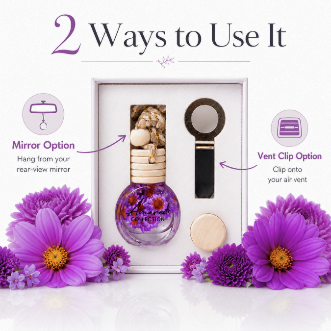 A boxed diffuser set displayed on a white background with decorative purple flowers. The set includes a round glass diffuser bottle with dried flowers, a wooden reed diffuser stick, a black-and-silver mirror, and a vent clip.