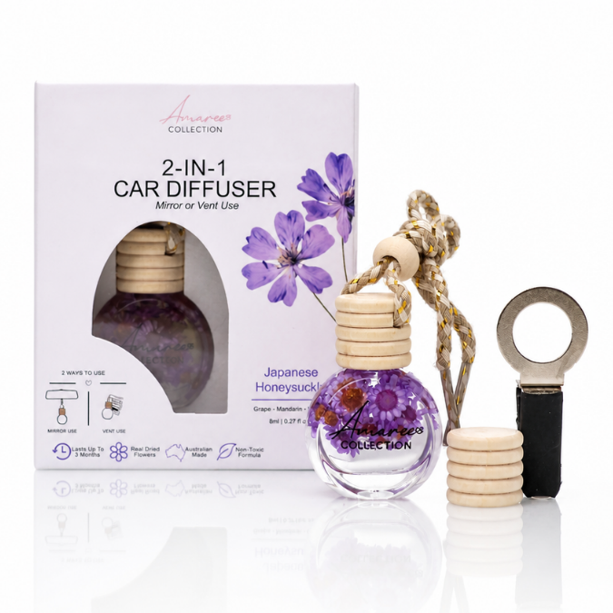 A 2-in-1 car diffuser set by Amara Collection, featuring a glass bottle with a purple floral pattern, a wooden cap, a decorative rope, a metal diffuser attachment, and its white packaging box with purple flowers.