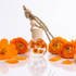 Perfume bottle with orange flowers and a wooden cap on a white background