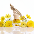 Car air freshener with wooden holder and clear bottle surrounded by yellow flowers on a reflective surface.