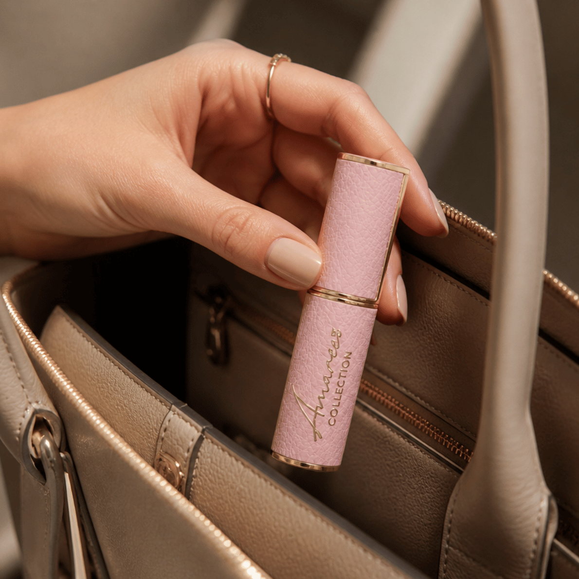 A close-up of a hand holding a pink textured lipstick tube with gold trim and the brand name &