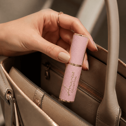 A close-up of a hand holding a pink textured lipstick tube with gold trim and the brand name &
