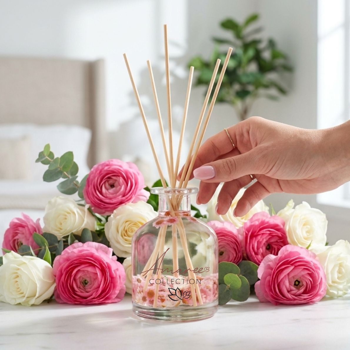 Hand holding a diffuser with floral design surrounded by pink and white flowers.