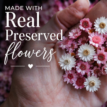 Hand holding pink and white preserved flowers with text &