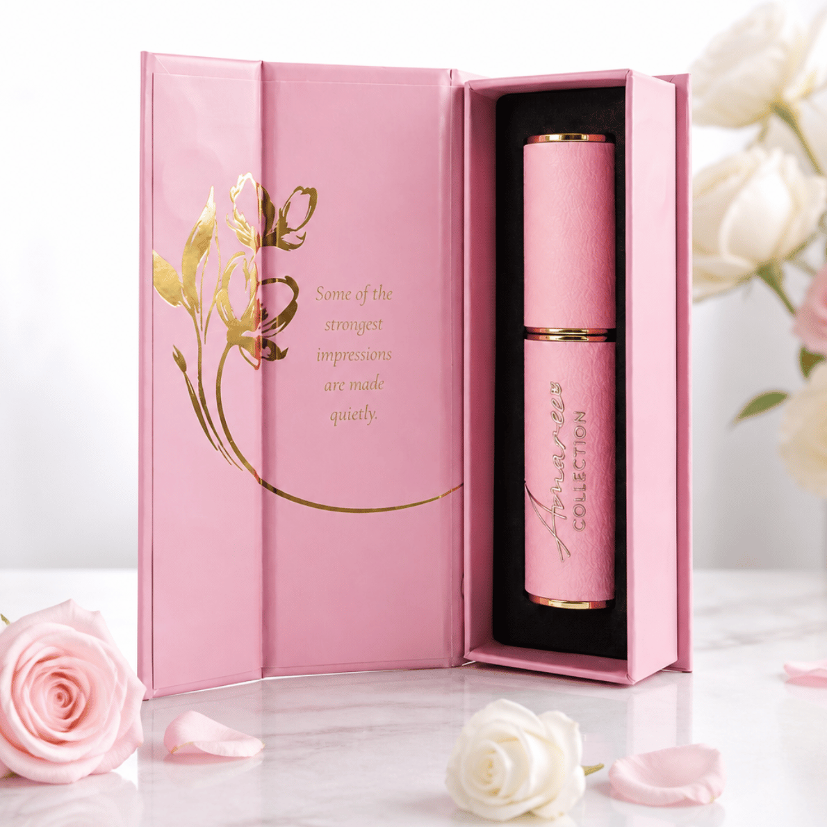 pink and gold refillable perfume case against a white background styled with pink and white roses in an elegant magnetic box