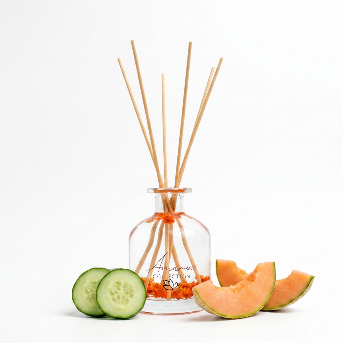 Reed diffuser with wooden sticks, sliced cucumber, and cantaloupe on a white background