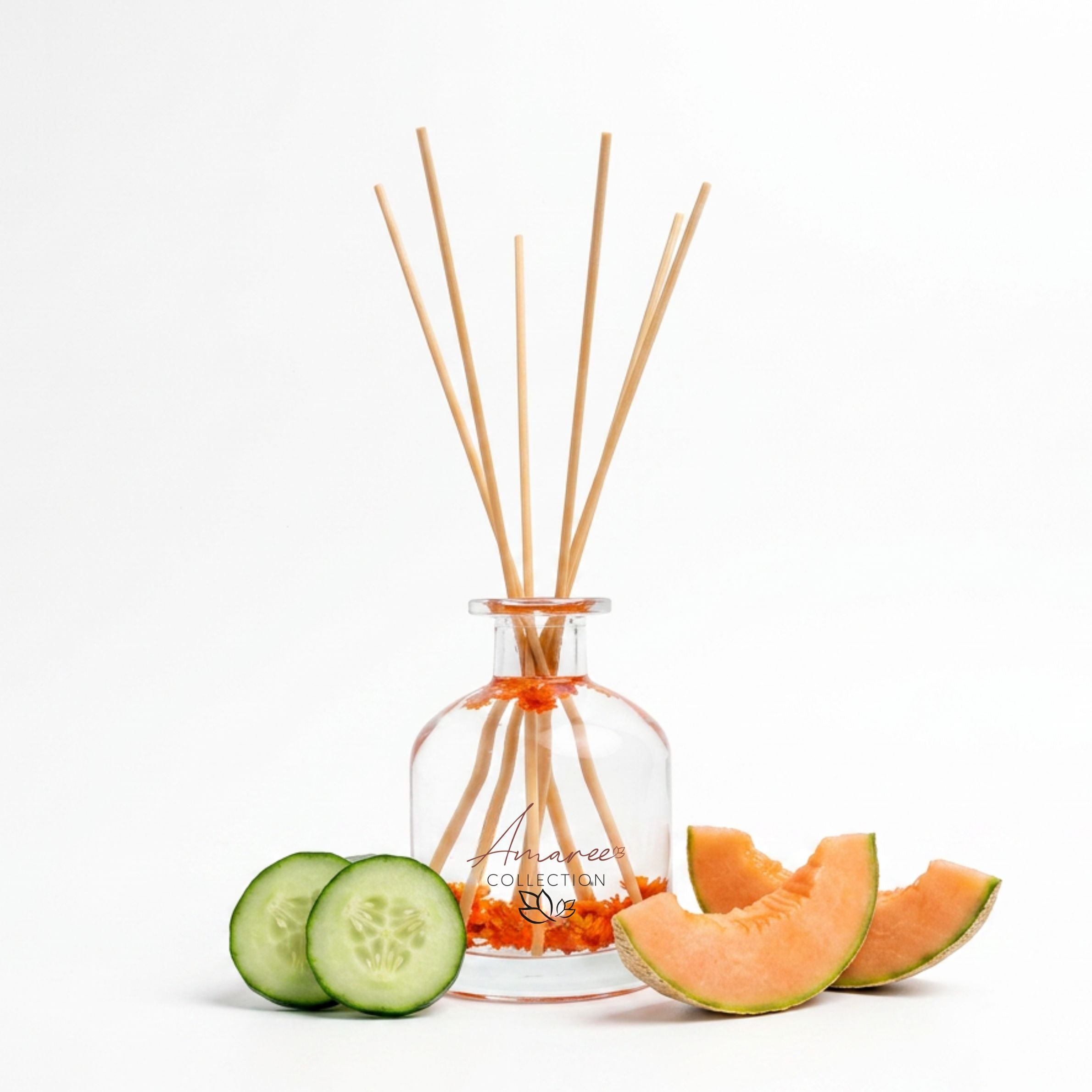 Reed diffuser with wooden sticks, sliced cucumber, and cantaloupe on a white background