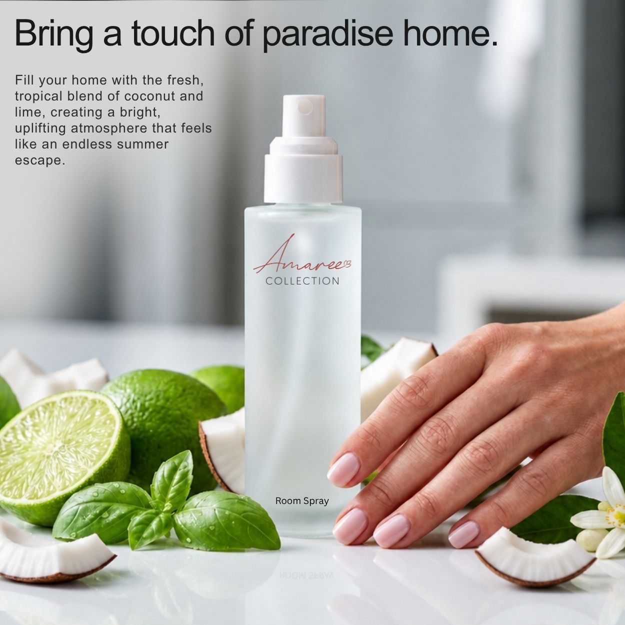 A frosted room spray bottle from Amaree Collection stands on a white surface with limes, basil, coconut, and a hand reaching toward it. Text on the left reads, &