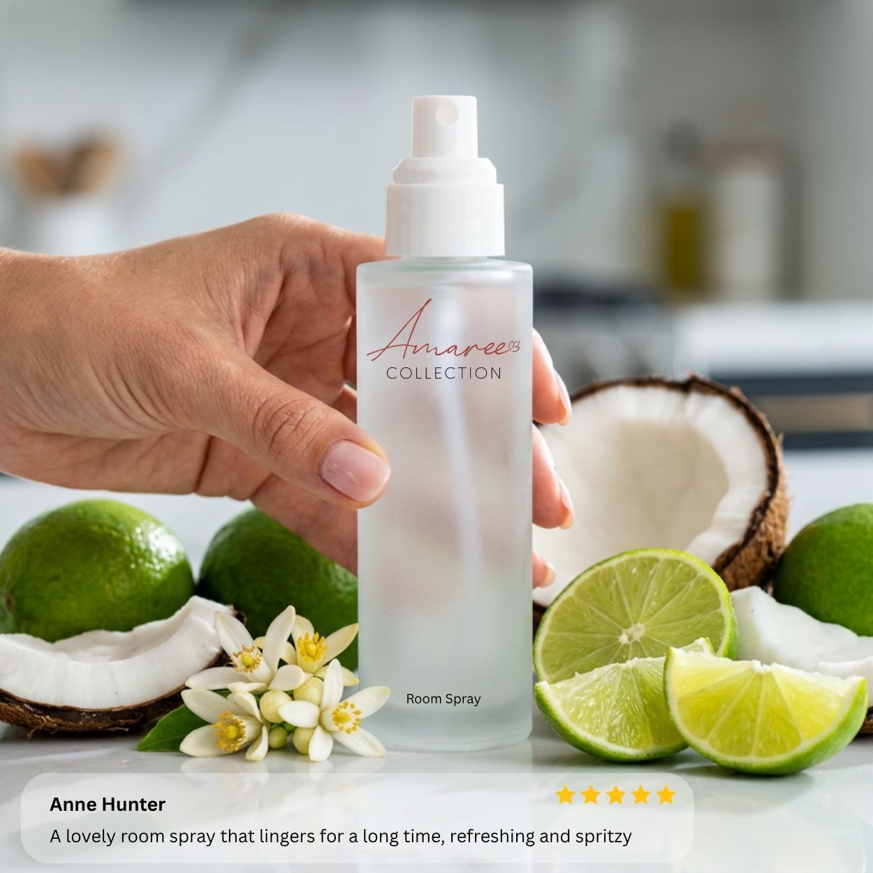 A hand holds a frosted glass room spray bottle labeled &