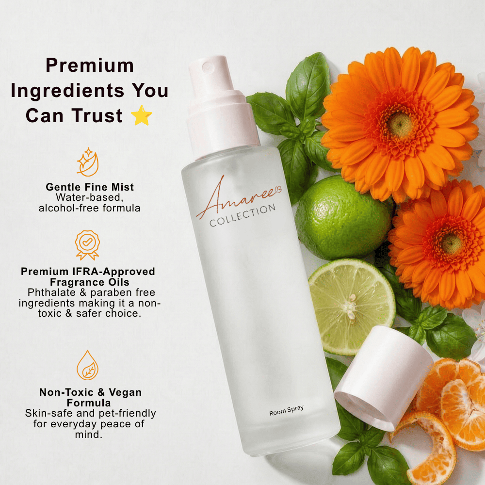 A bottle of Amaree Collection Room Spray with its cap off, styled with fresh limes, orange gerbera daisies, basil, and orange slices on a white background with text detailing its premium ingredients.