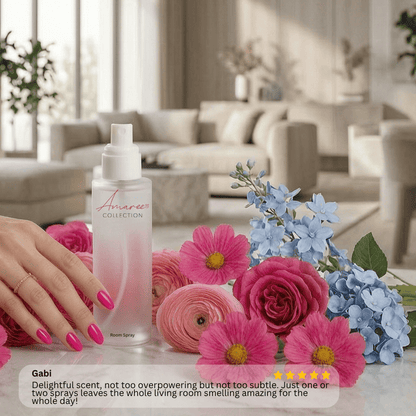 A hand with pink nails holds a frosted room spray bottle labeled &